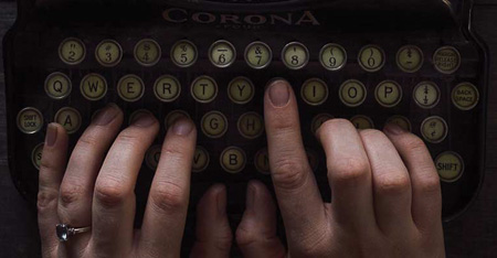 A close up photo of hands typing on an old fashioned typewriter